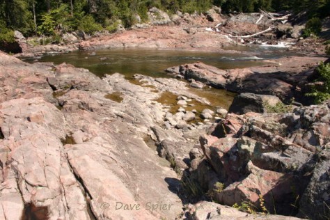 view across the pink granite bedrock toward the upper Chippawa Falls at upper right