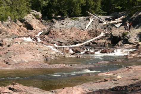 The upper Chippewa Falls was created by a vertical, gray, diabase dike cutting across the pink granite. Here the fault displaces the 65-foot thick dike by 30 feet upstream on the northwest (left) side of the river.